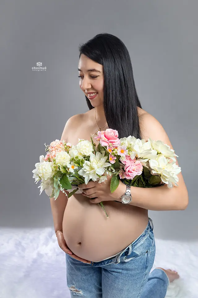 Futura mamá embarazada sosteniendo un ramo de flores, sesión de maternidad